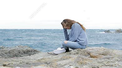 Sad teenager sitting on the beach in a windy day