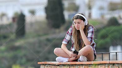 Sad teen listening to music on vacation