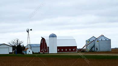 Farm buildings with active windmill on a cloudy day in Minnesota