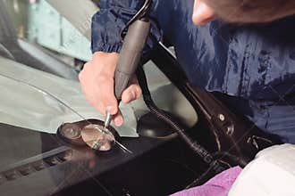Close up Car glaze worker fixing and repairing a windshield or windshield of a car at a garage service station. Drill