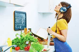 Woman in kitchen cooking with listening music