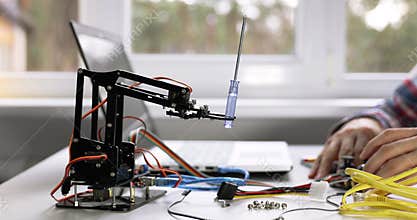 Robotics engineering - technician programming robot arm on computer