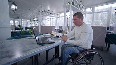 Online education, student disabled man on wheelchair uses modern laptop technology to learn from online lessons and