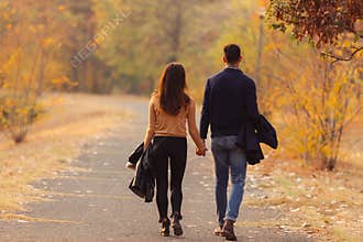 Young couple walking down the road filled with autumn leaves