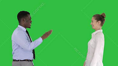 Young woman and young man in formal clothes give high five on a Green Screen, Chroma Key.