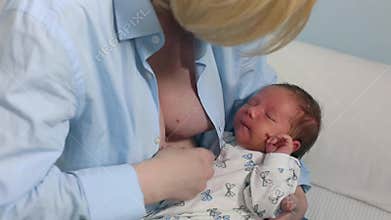 Mother breast feeding and hugging her baby.Young mother feeding breast her babyboy at home in blue-white room. Mom