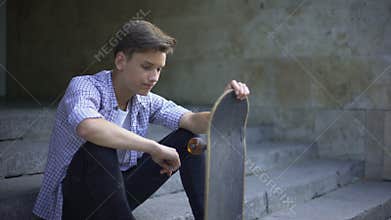 Sad lonely skater sitting alone with skateboard, bullying problem, teenager