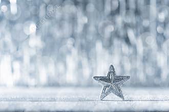 Shiny silver christmas star with defocused christmas lights in the background. Christmas background.