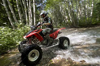 Female riding ATV through creek