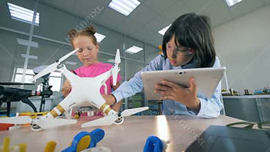 Working children inspect a drone, close up.