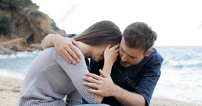 Man comforting to his sad friend on the beach