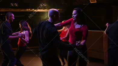Young energetic attractive couples dancing salsa, bachata, latin dance on open air party in evening time