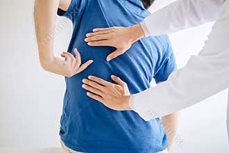Doctor physiotherapist treating lower back pain patient after while giving exercising treatment on stretching in the clinic,