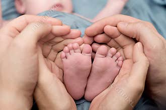 Feet of a newborn baby, toes in the hands of mom and dad, hands and nails of a child, the first days of life after birth,