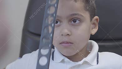 Portrait of handsome african american sitting in the chair of optometrist. Professional ophthalmologist checks the