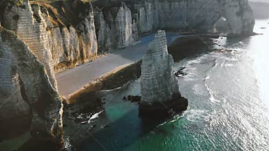 Drone panning above incredible natural eroded rock arch and pillar at famous white alabaster sea cliffs at Etretat.