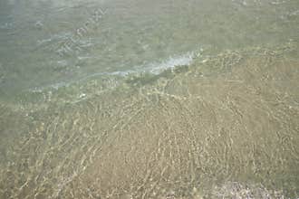 Close up the clarity of the sea that reflects the sun on the sand