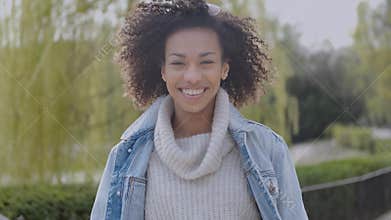 Happy and smiling mixed race girl with afro haircut walking at the park