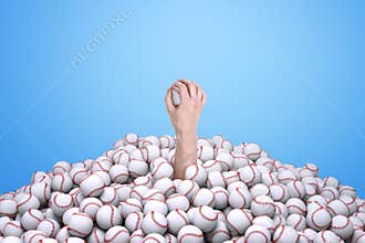 Man`s hand holding a baseball, emerging from under a big pile of baseballs.