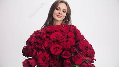 Attractive woman going to camera with bouquet of red roses