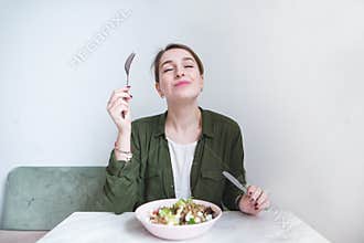 Woman eats a delicious salad. A sweet girl sits at the table, eats a plate salad and delights