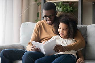 Happy family black father and kid daughter reading story book