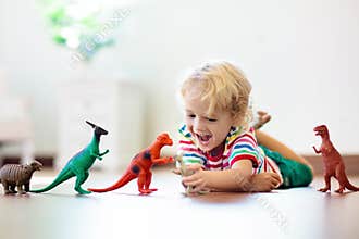 Child playing with toy dinosaurs. Kids toys