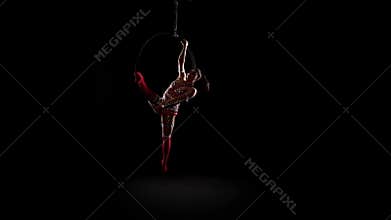 Girln hanging in scene for aerial acrobatics. Black background. Slow motion