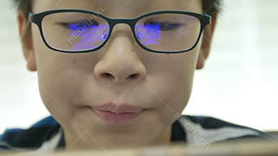 Close up of young asian boy playing games on smart phone with reflex blue box on glasses