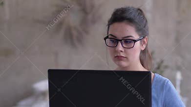 Portrait of freelancer girl in glasses working on laptop online sitting at home close-up