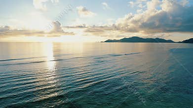 Sunset 4k footage over calm sea with tropical island silhouette on horizon. Flying the drone at low altitude over the