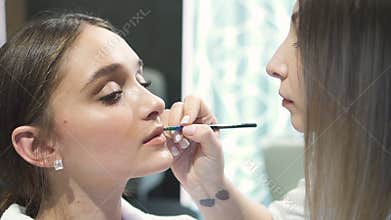 Gorgeous woman is sitting at cosmetic studio with elegance makeup.