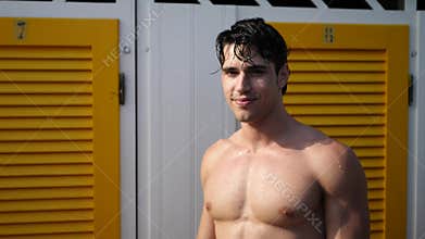 Handsome and muscular young man by beaach changing rooms