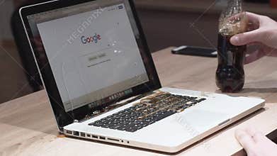 Odessa, Ukraine - November 11, 2018. The man inaccurately poured cola on a macbook laptop. Pouring liquid into a laptop pc. Broke