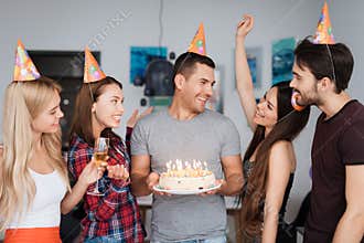 A guy`s birthday and his friends congratulate him. Guests are standing around the birthday boy. The guy is holding a