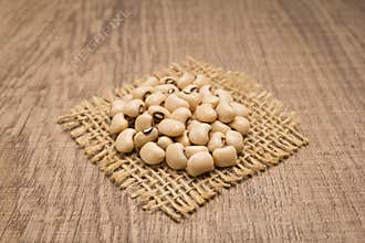 Black Eyed Pea legume. Grains on square cutout of jute. Wooden t