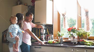 Happy young family preparing breakfast in the kitchen. Slow motion