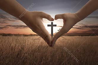 People hand making heart sign with bright cross inside