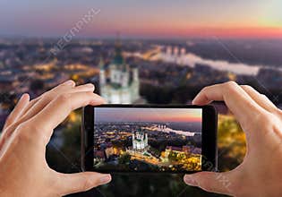 Travel concept. Hands making photo of St. Andrew`s Church Kiev Ukraine. Cityscape from a height.