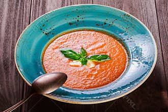 Tomato gazpacho soup with basil, feta cheese, ice and bread on dark wooden background, Spanish cuisine. Ingredients on table
