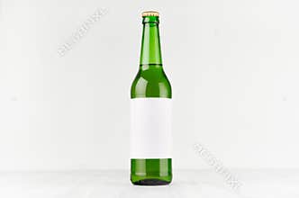 Green longneck beer bottle 500ml with blank white label on white wooden board, mock up.