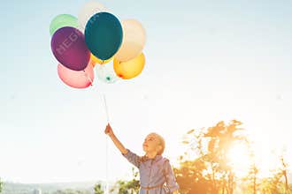 Girl holding balloons in one hand looking to them