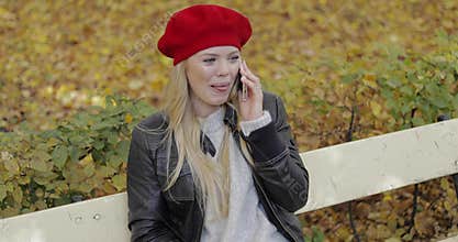 Cheerful woman in beret speaking on phone