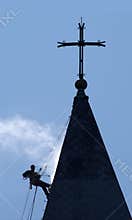 Silhouette of the alpinist cleans church roof