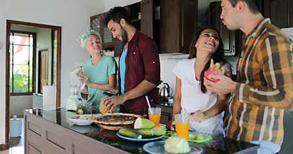 Two Couples In Kitchen Cooking Together, Young Woman And Man Group Talking Cut Vegetables And Fruits Prepare Healthy