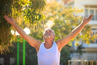 Grey Bearded Old Man in Vest Lifts Hands Looks up in Park