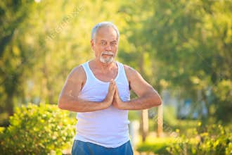 Grey Bearded Old Man in White Vest Shows Yoga in Park