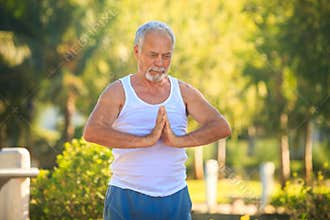 Grey Bearded Old Man in White Vest Shows Yoga in Park