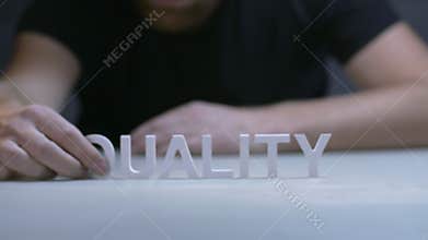Man hands composition word quality from white letters on gray background