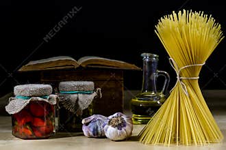 Pasta and olive oil on an old kitchen table. Recipes in old books in the kitchen on a wooden table.